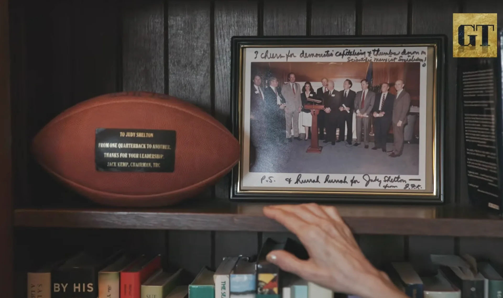 Framed photograph signed by Jack Kemp and a football inscribed to Judy Shelton, displayed on Dr. Shelton's shelf